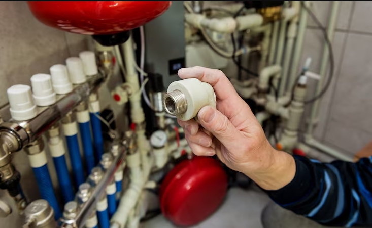 Plumber inspecting a residential plumbing manifold and pressure fittings to ensure proper water distribution and flow.
