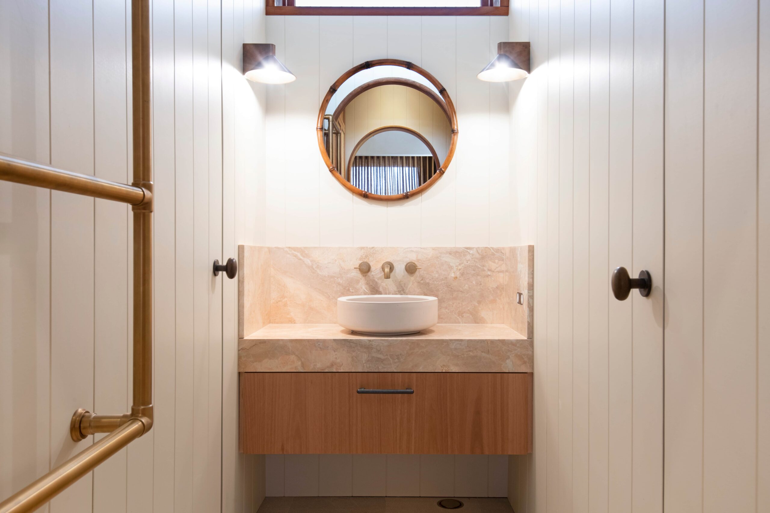 Modern bathroom with round mirror, vessel sink, marble vanity, wood cabinet—expert bathroom & ensuite plumbing displayed.