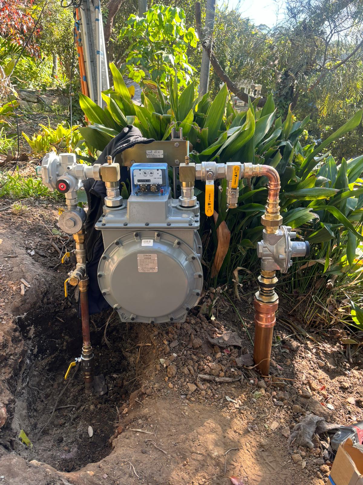 Newly installed gas meter with pipes and valves for Gas Fitting for Businesses, outdoors near plants and equipment.
