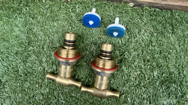 geotagged-brass-plumbing-valves-red-o-rings-blue-plastic-components-768x432 - SXP Plumbing - SXP Plumbing Two brass garden valves with blue handles lying on artificial grass (outdoor irrigation components).